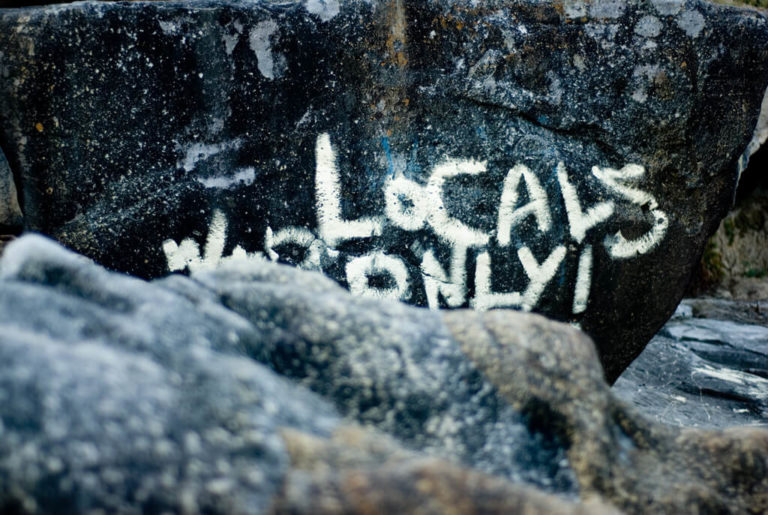 Rock with white graffiti reading, Locals Only!