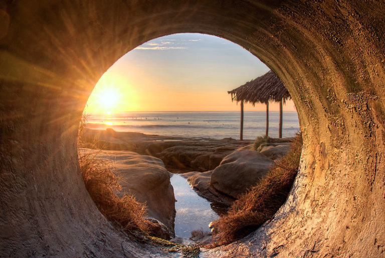 Beach sunset from tunnel with tiki hut in the sand