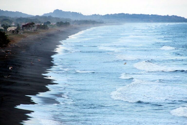 Water crashing against black sand at Playa Hermosa beach in Costa Rice